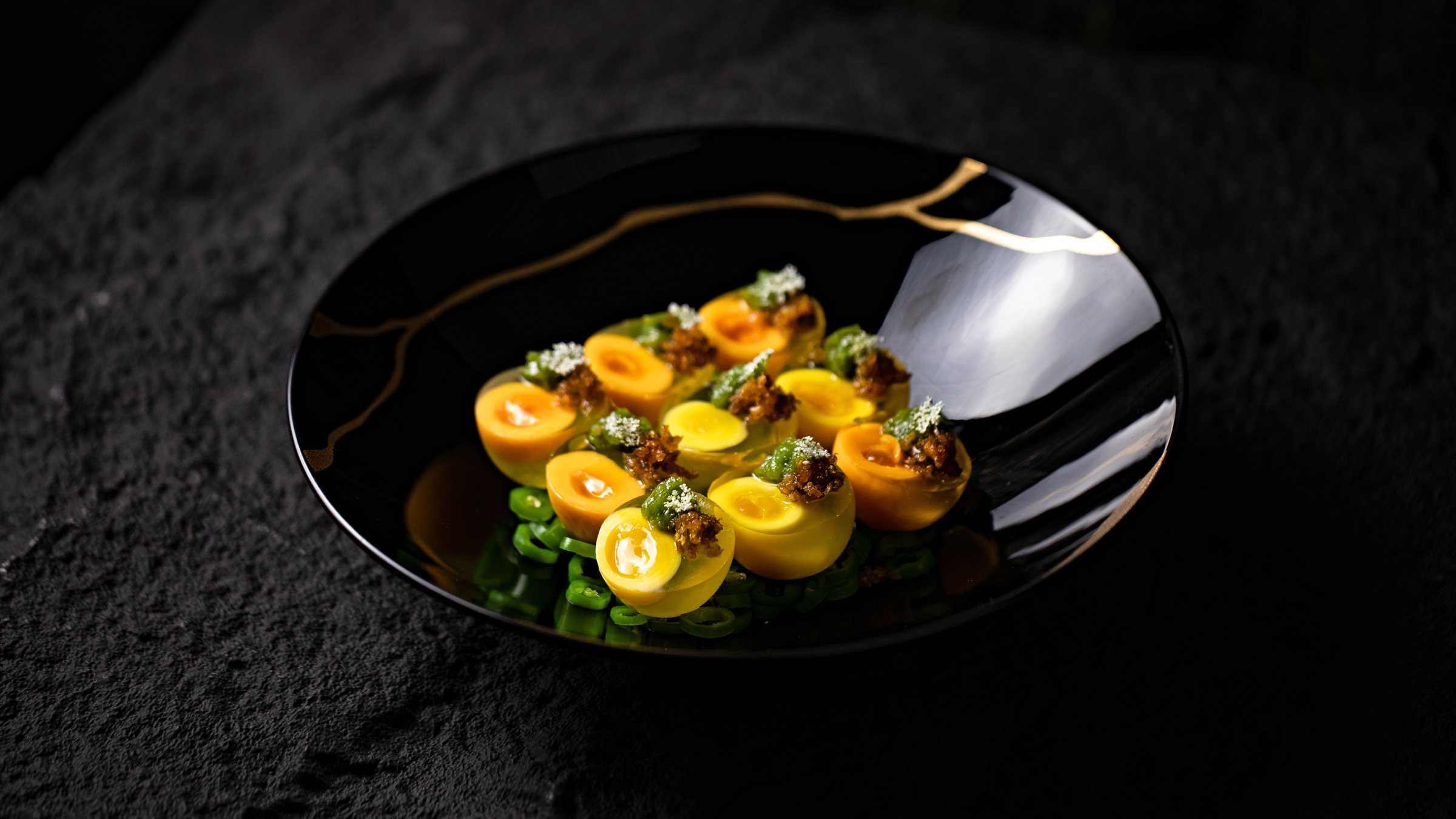 Elegant fine-dining dish on a black plate with gold detail